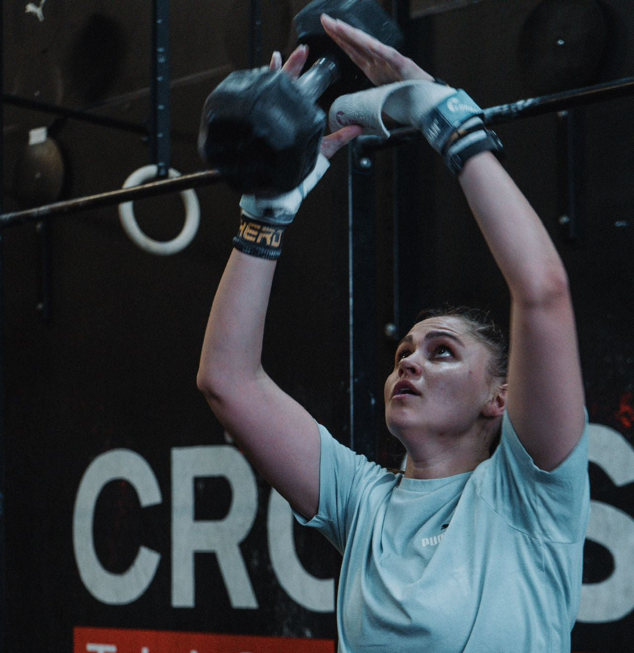 Person lifting weights in a gym setting with 'Crossfit' branding.
